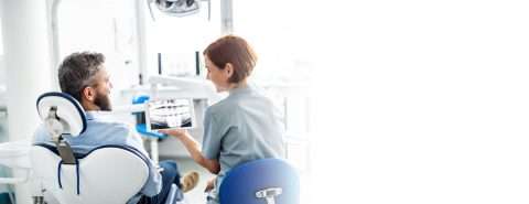 Female dentist in Vista, CA reviewing digital x-rays with male patient at North County Cosmetic and Implant Dentistry