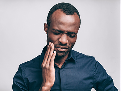 Man rubbing his jaw in pain, needing dental treatment at North County Cosmetic and Implant Dentistry in Vista, CA